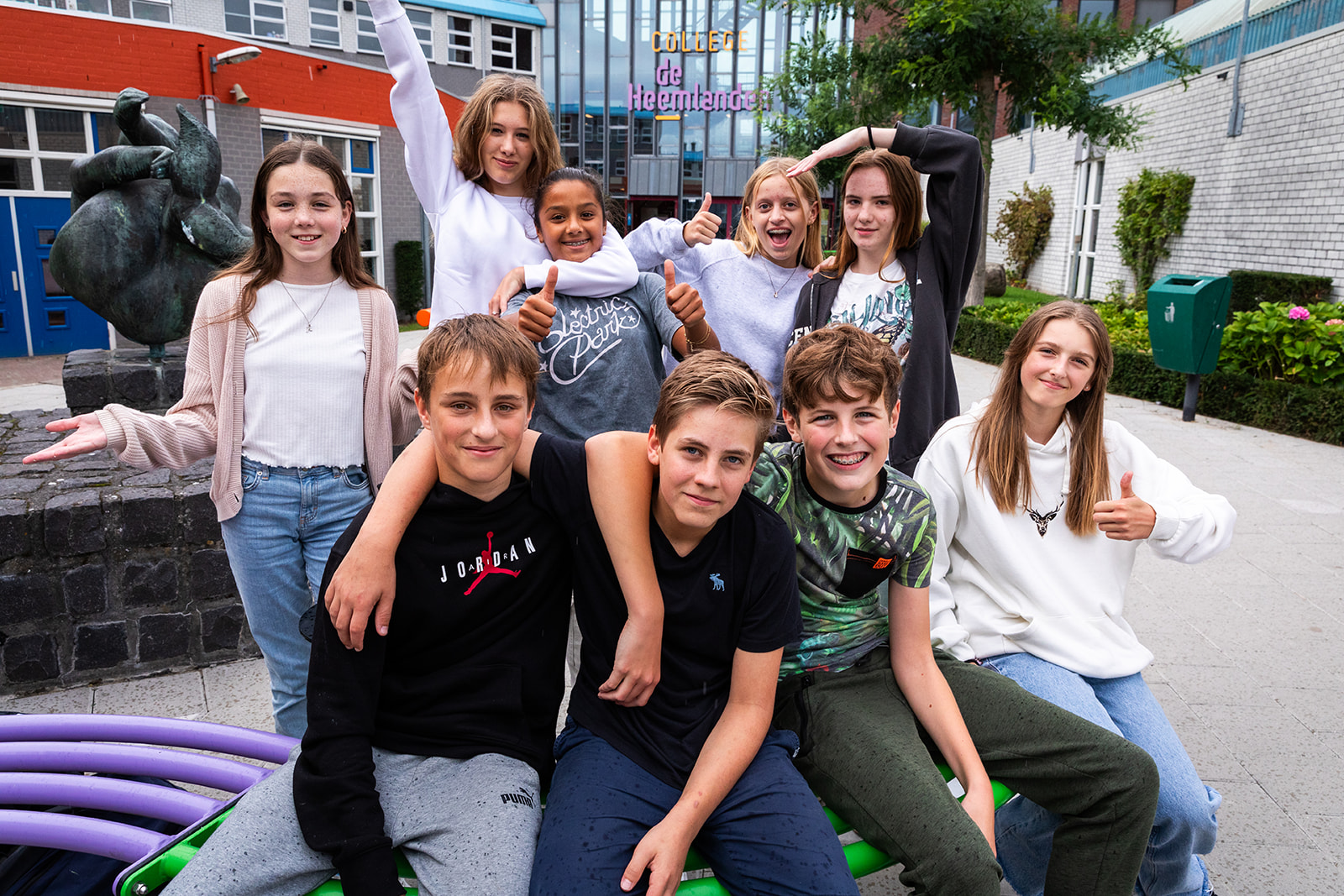 Blije groep leerlingen van College de Heemlanden in Houten voor het schoolgebouw