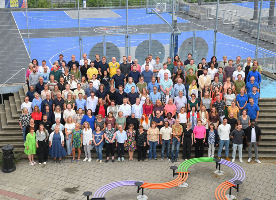 Team van College de Heemlanden op de foto voor het schoolgebouw op de trap buiten